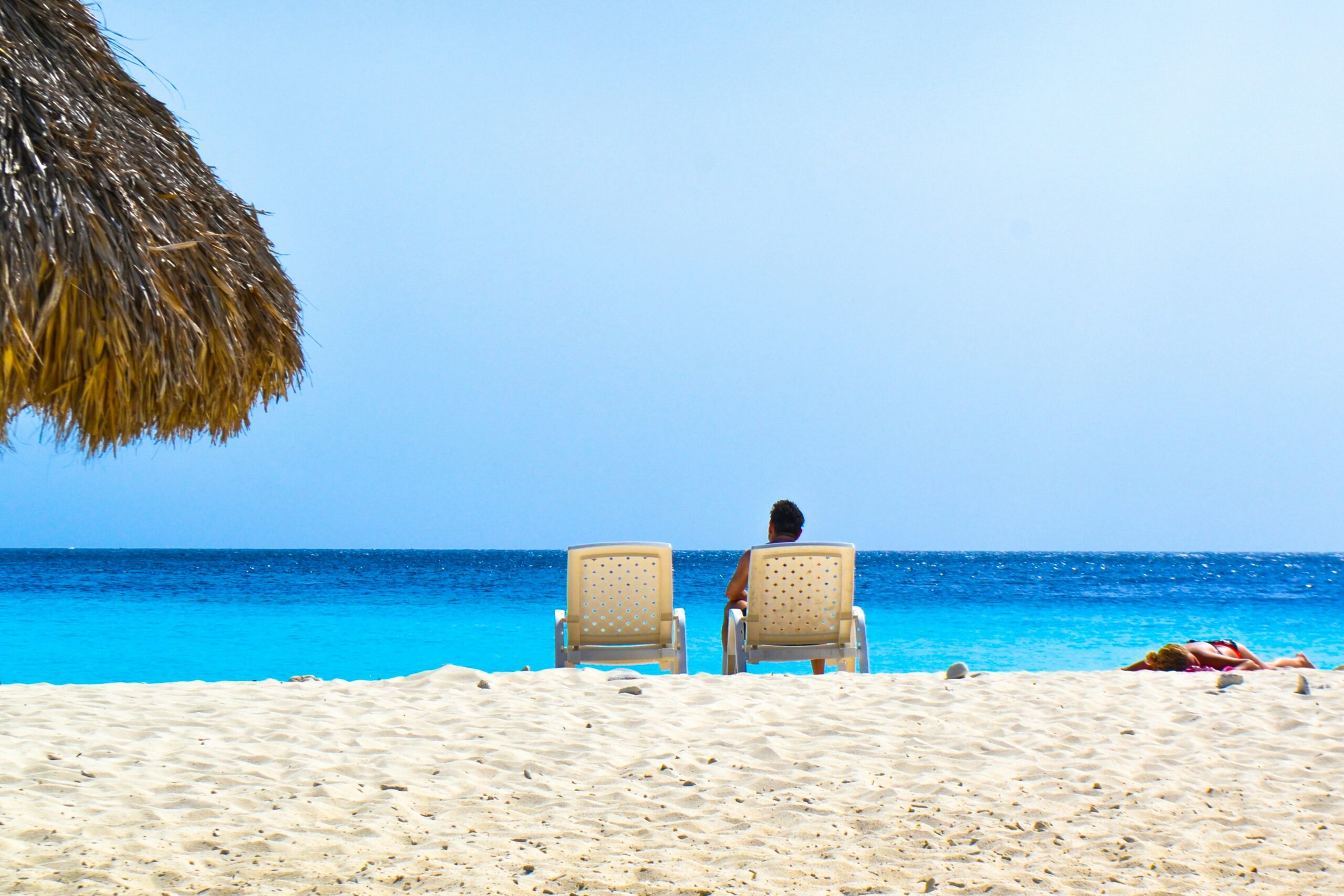 Person relaxing on a beach chair by the ocean.